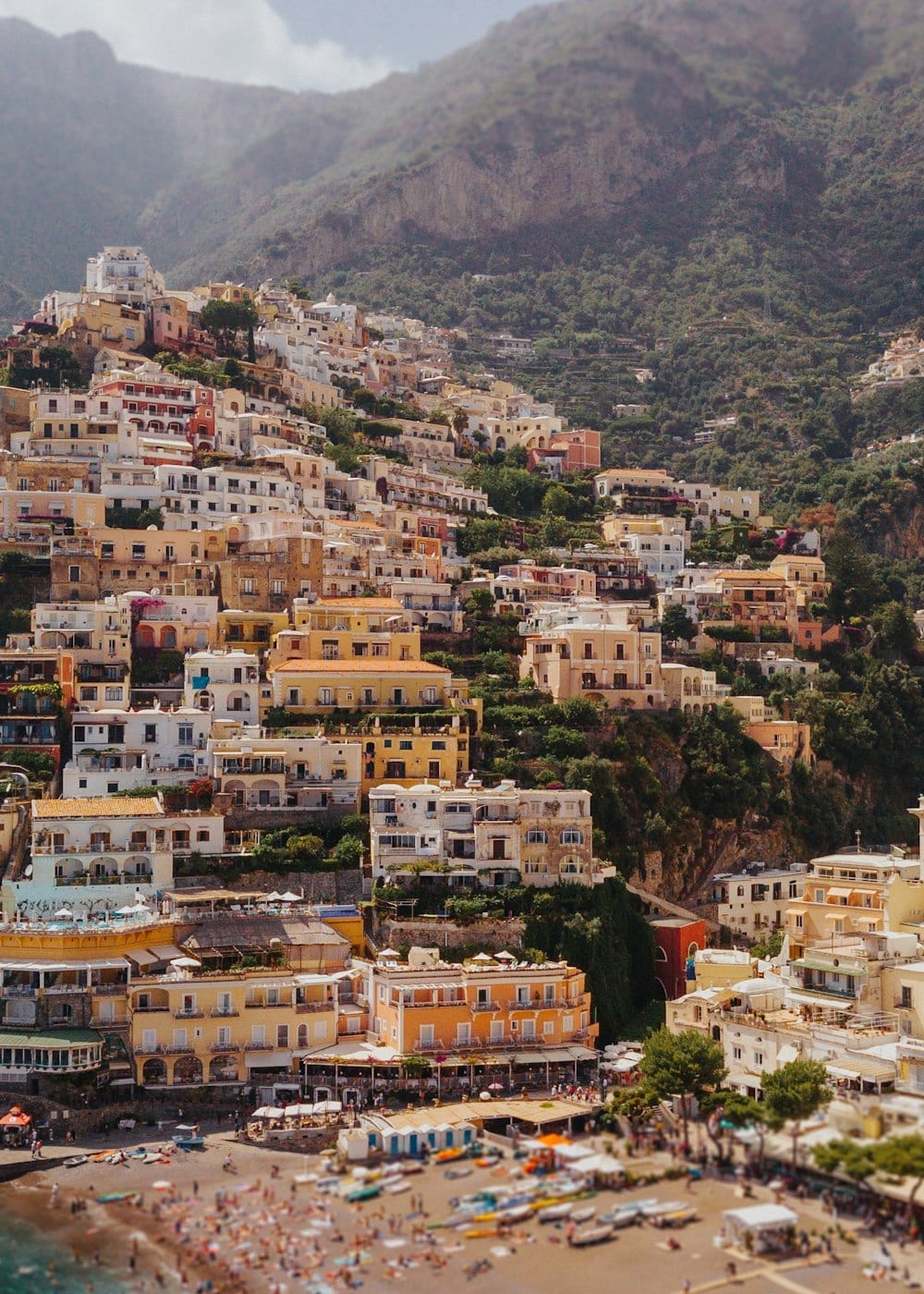 Pale houses stacked up a green hillside above the coast