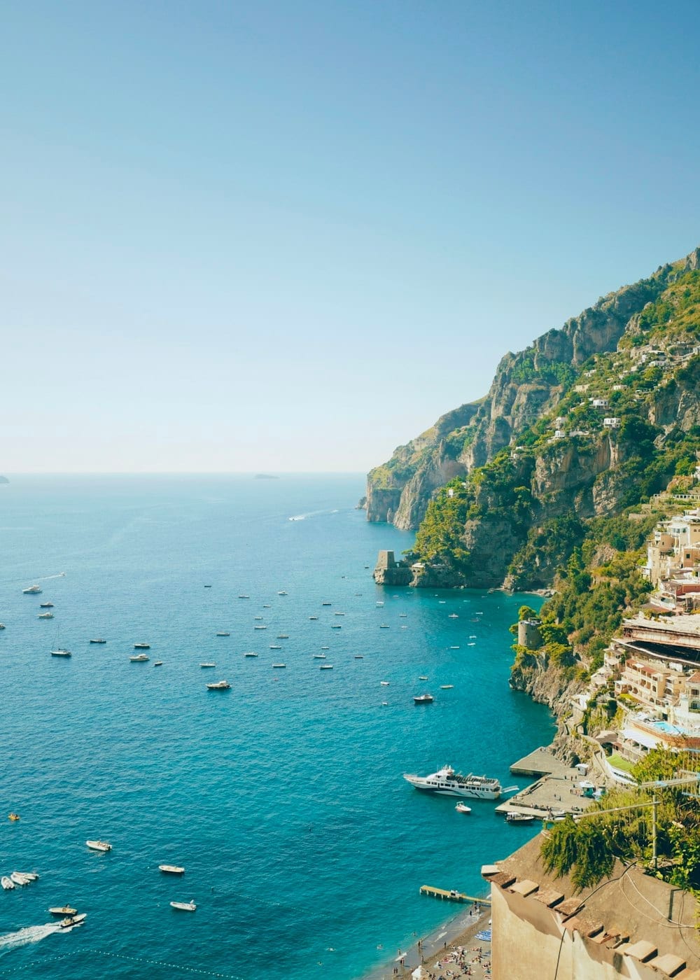 Turquoise water and small boats below a cliff