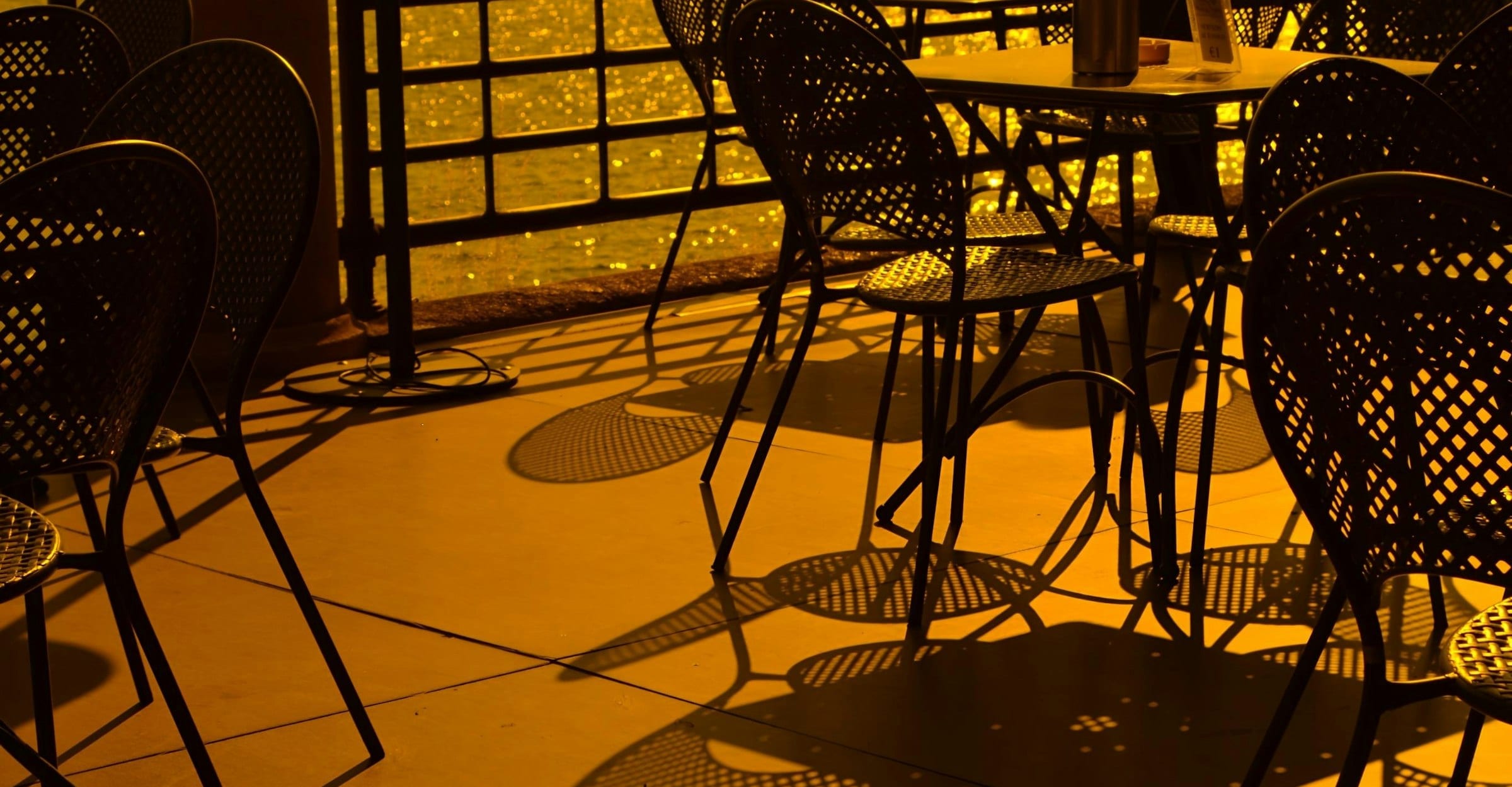 Empty café tables on a terrace in low golden afternoon light