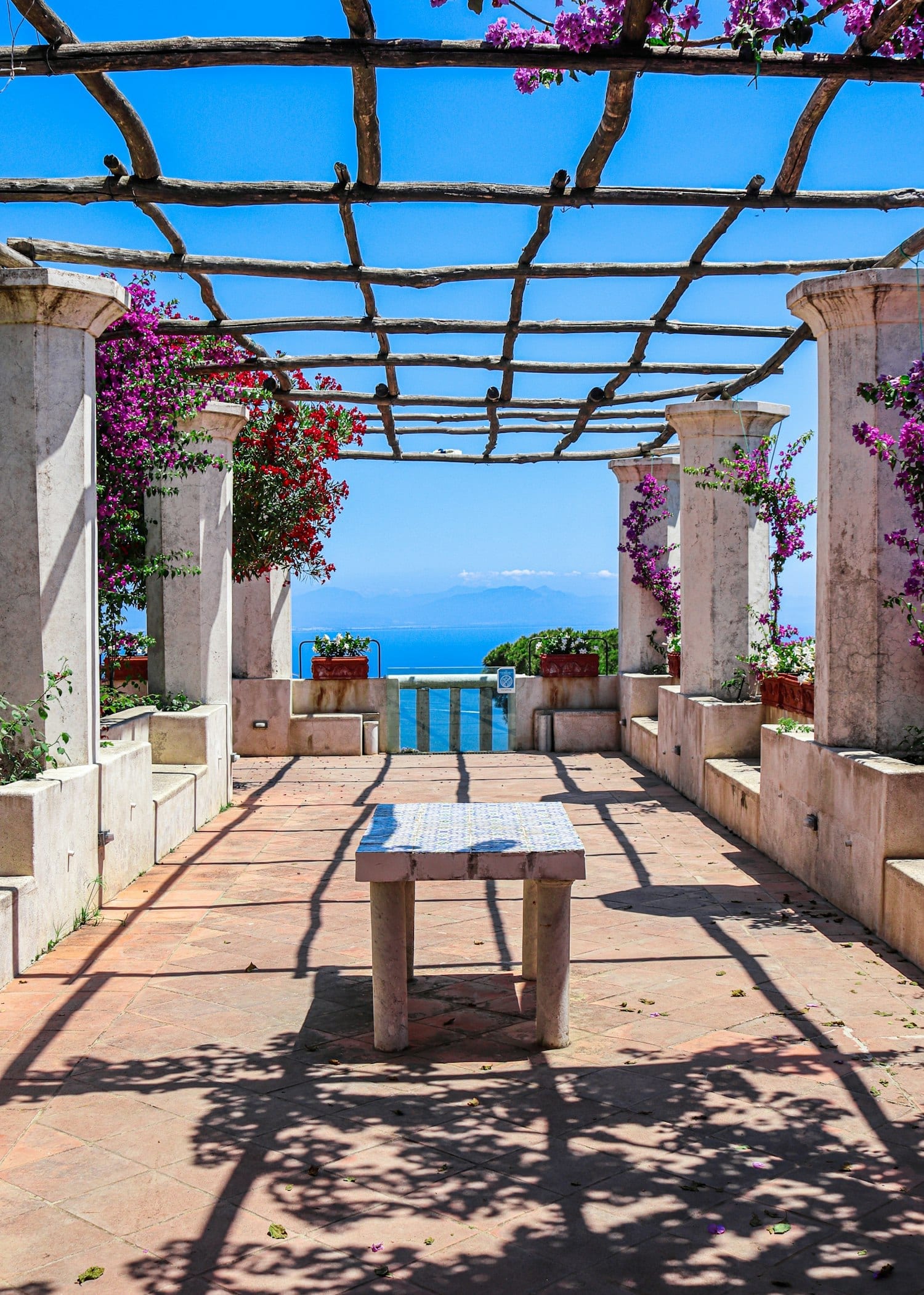 A colonnaded pergola hung with bougainvillea, opening onto the sea