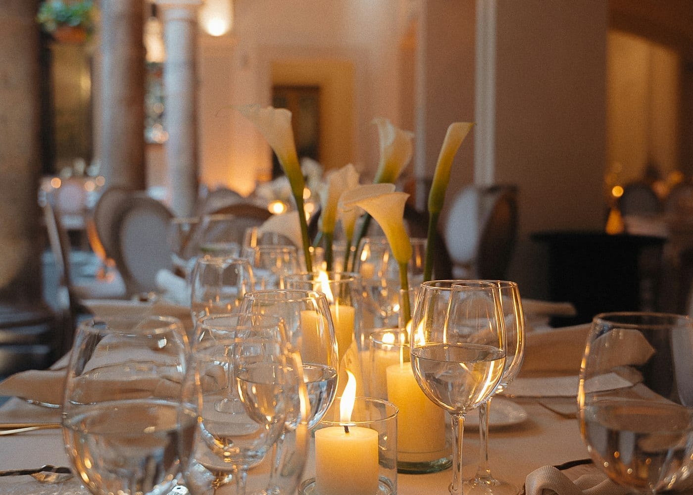 A dining room table laid with glasses and lit by candles